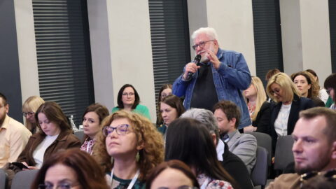 osoba zadająca pytanie przez mikrofon na widowni konferencji