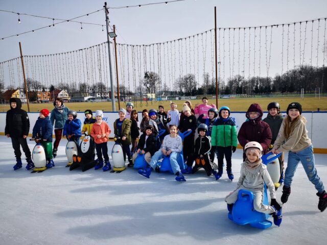 Łyżwiarze na mobilnej tafli pleszewskiego lodowiska na stadionie miejskim podczas grupowej jazdy.