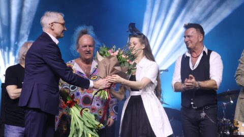 Burmistrz wręczający kwiaty na scenie podczas koncertu.