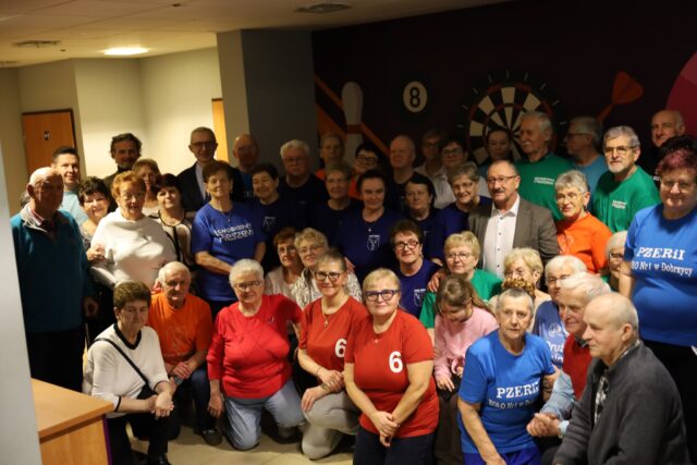 Uczestnicy turnieju bowlingowego na grupowym zdjęciu w kręgielni wspólnie z orgnizatorami.