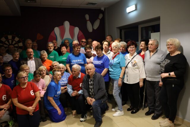 Uczestnicy turnieju bowlingowego na grupowym zdjęciu w kręgielni wspólnie z orgnizatorami.