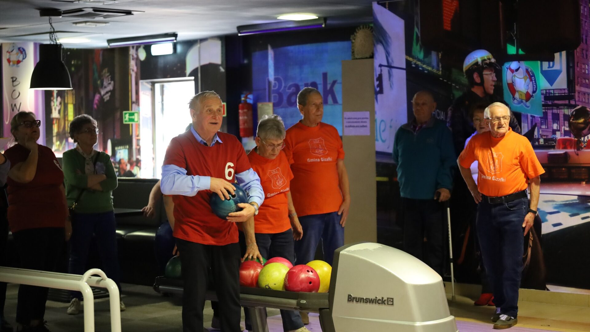 Uczestnicy turnieju bowlingowego podczas rywalizacji z kulami w rękach.