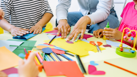 Ręce nauczyciela i dzieci pracujące przy kreatywnych zajęciach.
