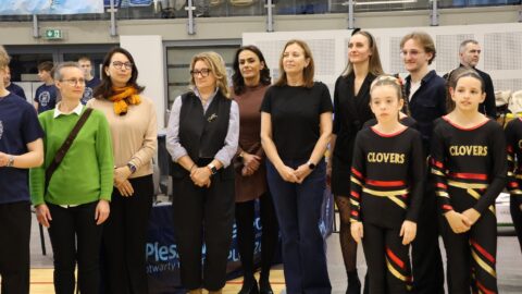 Sędziowie turnieju aerobiku w hali sportowej prezentujący się publiczności.