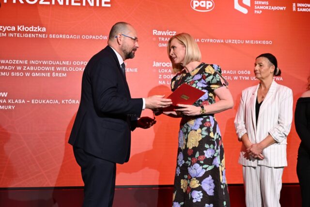 Zastępczyni burmistrza odbierająca statuetkę podczas gali konkursowej na scenie. 